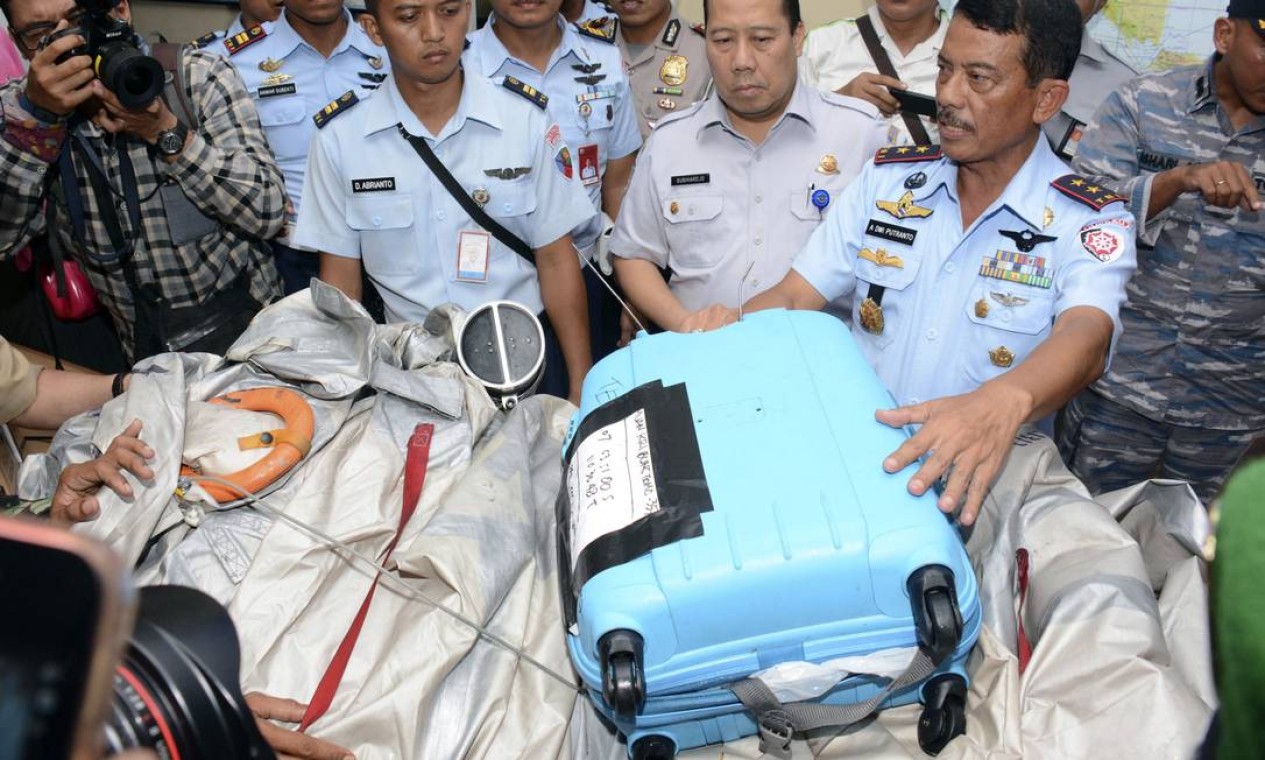 Comandante indonésio apresenta objetos retirados do mar que pertenciam ao voo da AirAsia, como uma mala azul e o que parece ser um tanque de oxigênio, na base aérea de Pangkalan Bun Foto: Dewi Nurcahyani / AP