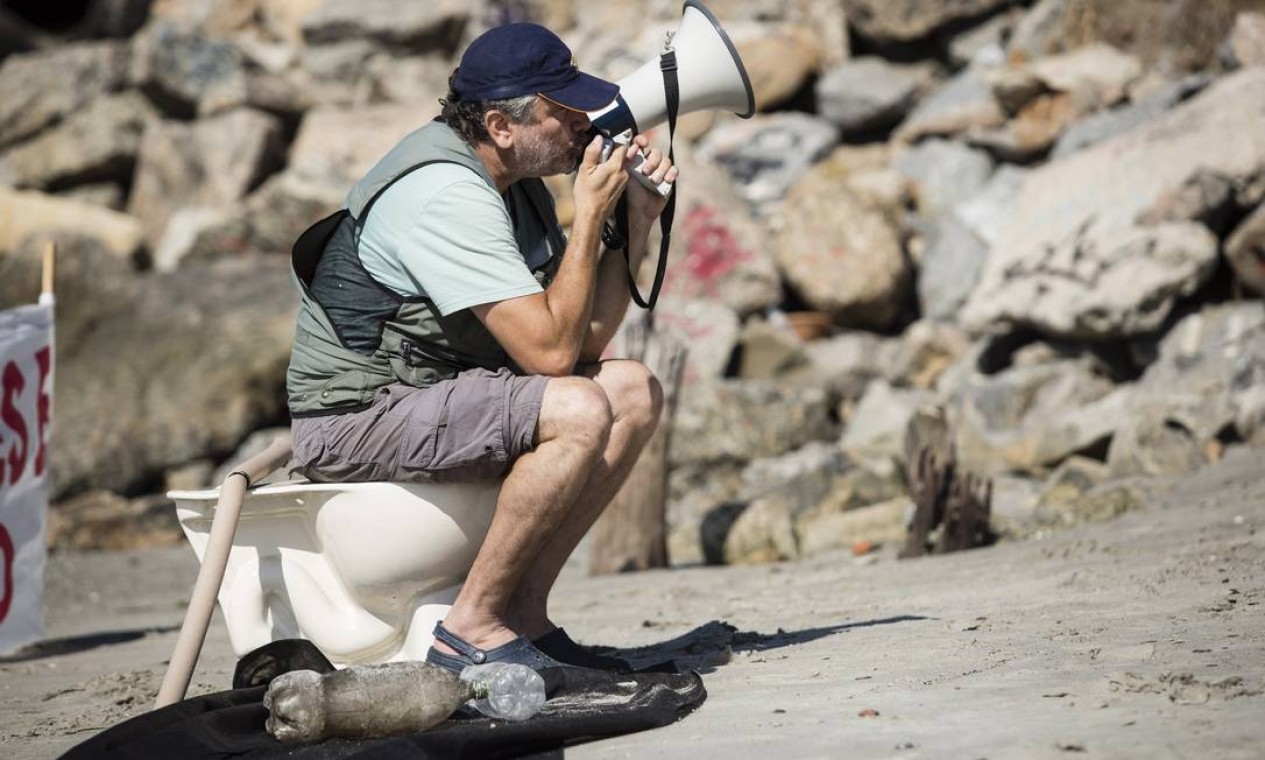 Em protesto, o biólogo Mario Moscatelli fica sentado em um vaso sanitário, na Praia de Botafoto Foto: Fernando Lemos / Agência O Globo