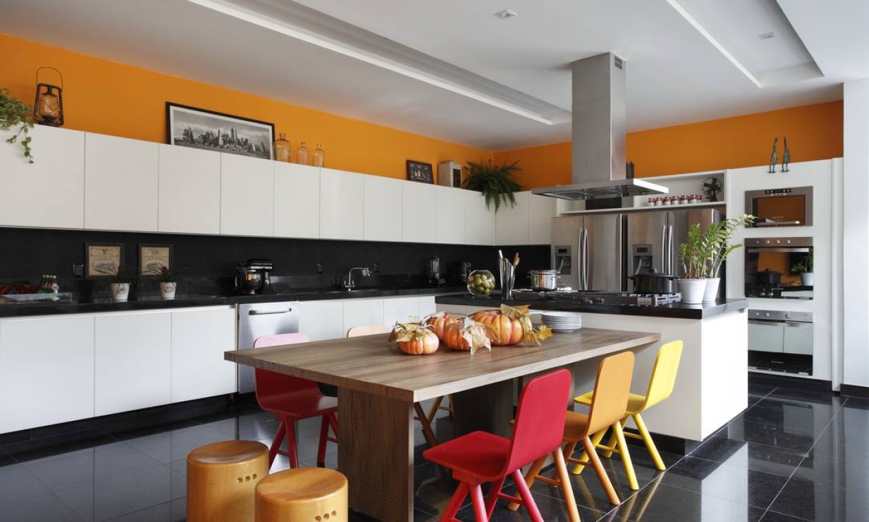 A cozinha preto e branca ganha vida com cadeiras em tom do por do sol e o laranja do roda teto Foto: MCA Studio / Divulgação