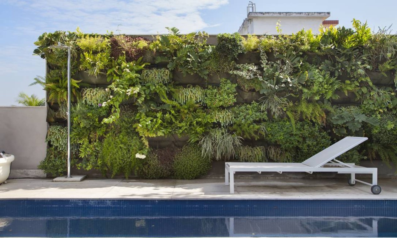 Ladeando a piscina em forma de raia, o jardim vertical traz o verde para a varanda Foto: MCA Studio