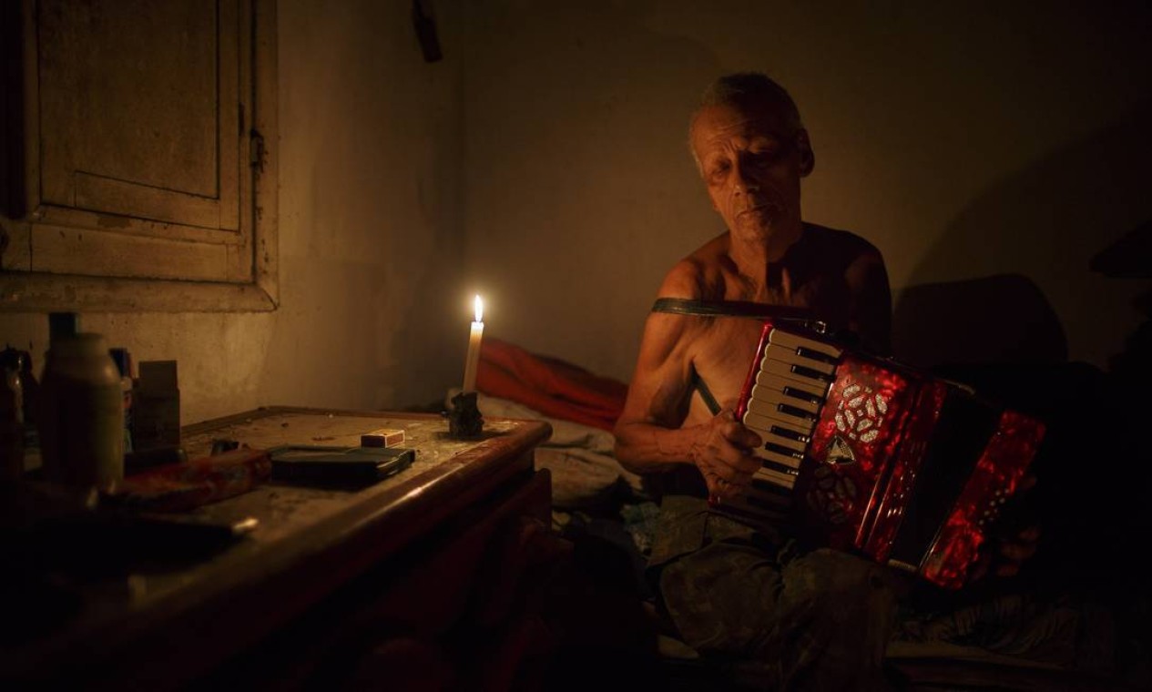 Seu Arnaldo toca seu acordeon de oito baixos no quarto onde dorme ouvindo rádio de pilha Foto: Daniel Marenco / Agência O Globo