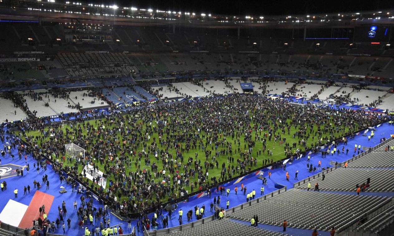 Espectadores que assistiam à partida entre França e Alemanha no Stade de France, em Saint-Denis, ao norte de Paris, aguardam no campo de jogo para sairem do estádio, após ataques terroristas à bomba nas imediações do estádio Foto: FRANCK FIFE / AFP