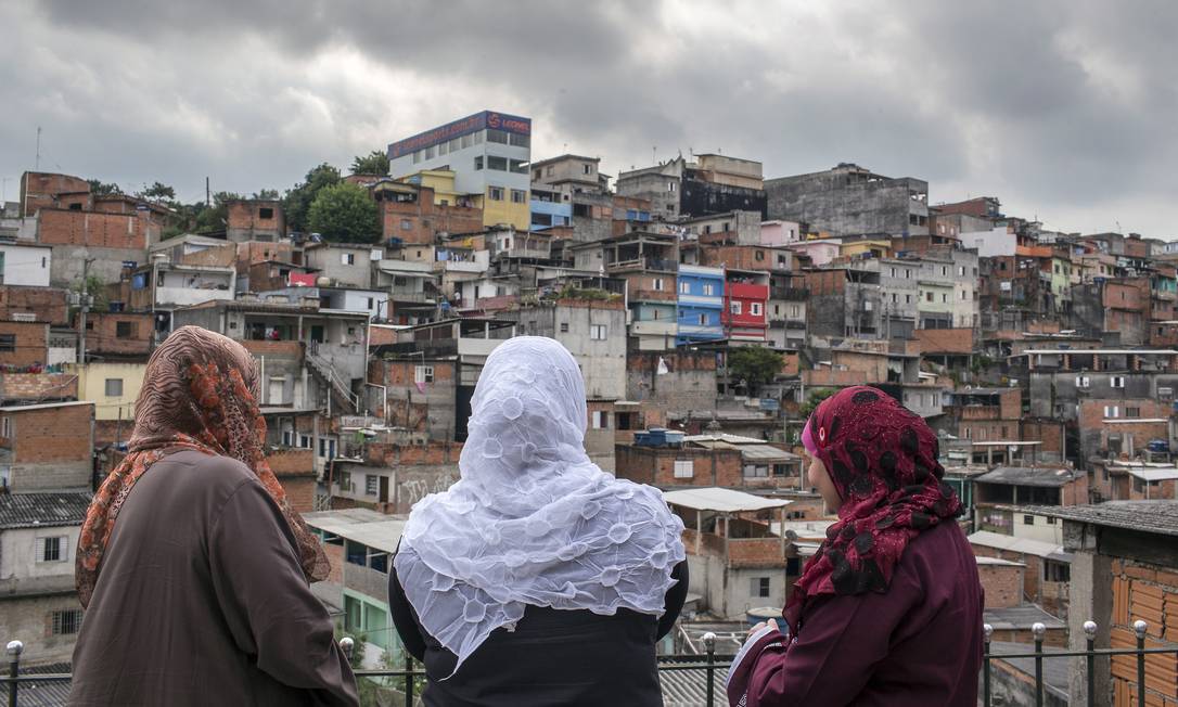 Usando os tradicionais véus, mulheres muçulmanas observam a comunidade do terraço de uma casa na periferia de São Paulo: islamismo vem crescendo no país no rastro da mensagem de igualdade racial e justiça social Foto: Edilson Dantas / Agência O Globo