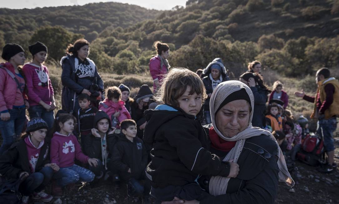 
Mulher e filho vindos da Turquia esperam com outras famílias para tirar fotos no registro de entrada na chegada à Ilha de Lesbos, na Grécia. Integrantes da minoria religiosa escaparam da perseguição violenta do Estado Islâmico
Foto: The New York Times/26-11-2015