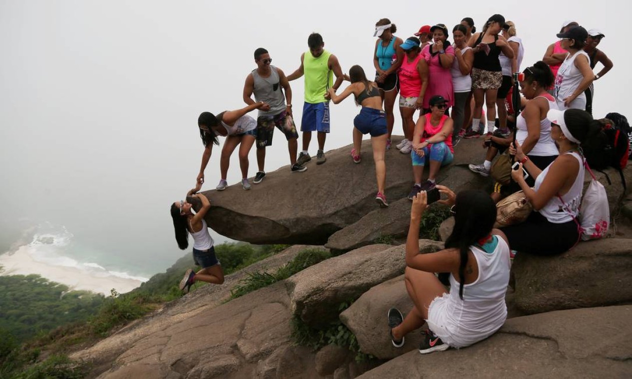 A fila sobre a pedra para a foto: enquanto jovem tenta se pendurar na rocha, outros esperam o seu minuto de fama no Instagram Foto: Custódio Coimbra / Agência O Globo