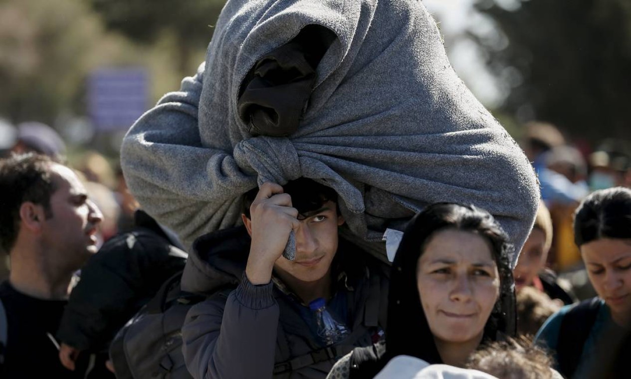 Depois da checagem de documentos, refugiado sírio carrega seus pertences ao sair do campo em direção à fronteira de Schisto, cidade próxima à capital grega, Atenas Foto: ALKIS KONSTANTINIDIS / REUTERS