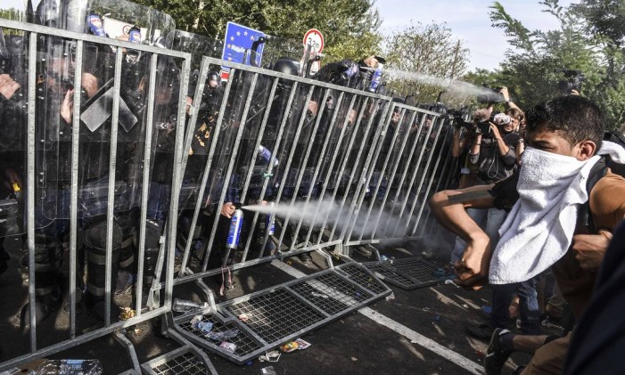 Policiais húngaros usam spray de pimenta para afastar imigrantes na fronteira com a Sérvia, em setembro de 2015 Foto: ARMEND NIMANI / AFP