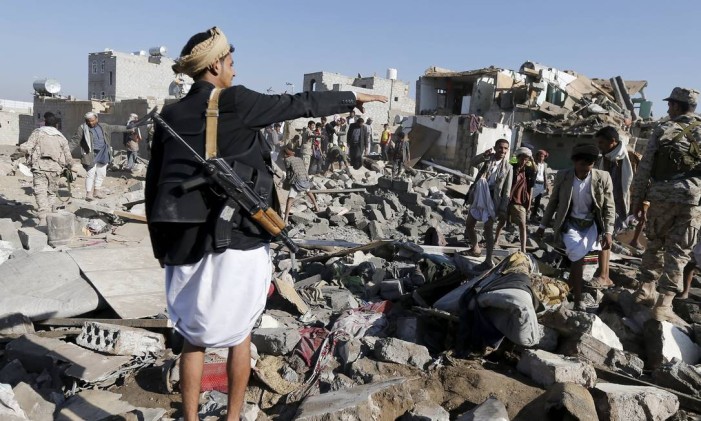Um homem armado gesticula em meio aos escombros deixados nos arredores do aeroporto de Sanna, no Iêmen, após ataque aéreo atribuído às forças sauditas Foto: KHALED ABDULLAH / REUTERS