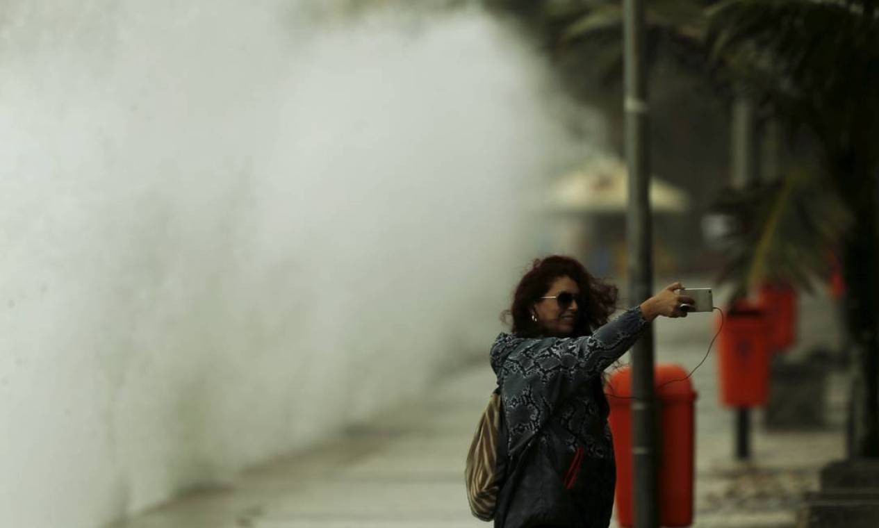 Mulher faz selfie com a onda que atinge o calçadão Foto: Gabriel de Paiva / Agência O Globo