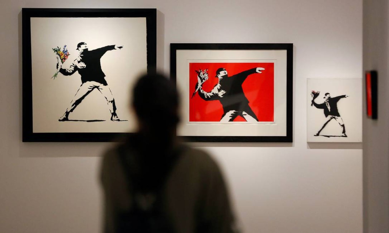 Homem observa as versões de 'Flower Thrower', de Banksy, expostas em Roma. Originalmente localizada em Jerusalem, a obra foi vista pela primeira vez em 2003 Foto: TONY GENTILE / REUTERS