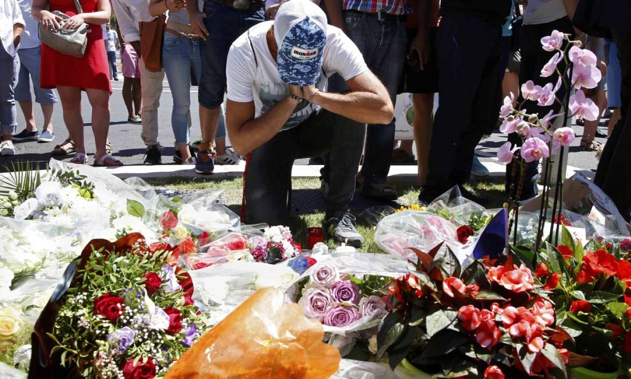 Homem homenageia vítimas em memorial com flores após França ser atingida por novo atentado terrorista que choca o país Foto: PASCAL ROSSIGNOL / REUTERS