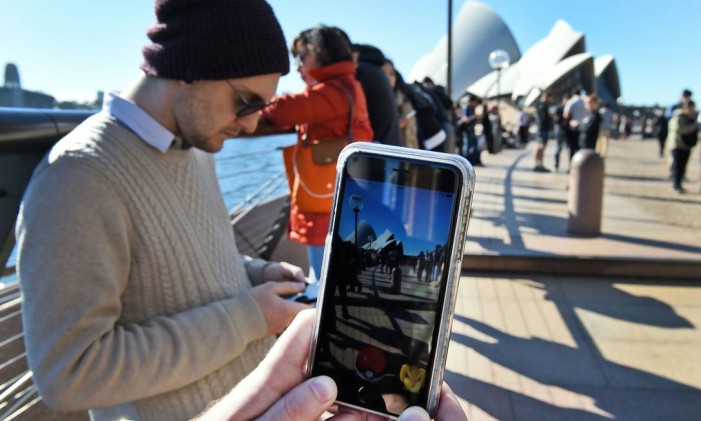 (FILES) This file photo taken on July 15, 2016 shows dozens of people gathering to play Pokemon Go in front of the Sydney Opera House.
A small Sydney suburban park that attracted thousands of Pokemon Go players, causing the grassy spot to turn to mud, has been removed from the popular mobile game on August 2, 2016 after complaints of chaos. / AFP PHOTO / WILLIAM WEST Foto: WILLIAM WEST / AFP