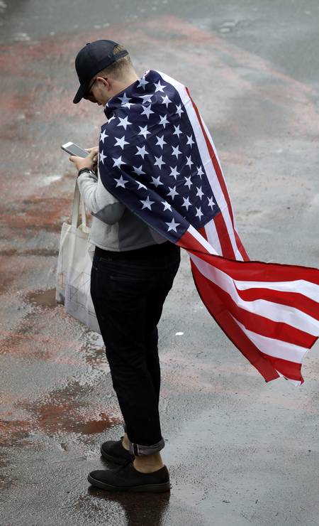 O torcedor Norte Americano aproveitou a bandeira para se proteger da chuva Foto: Eduardo Verdugo / AP