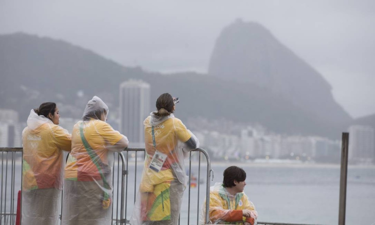 Com capas de chuva, voluntários observam o mar em Copacabana Foto: Márcia Foletto / Agência O Globo
