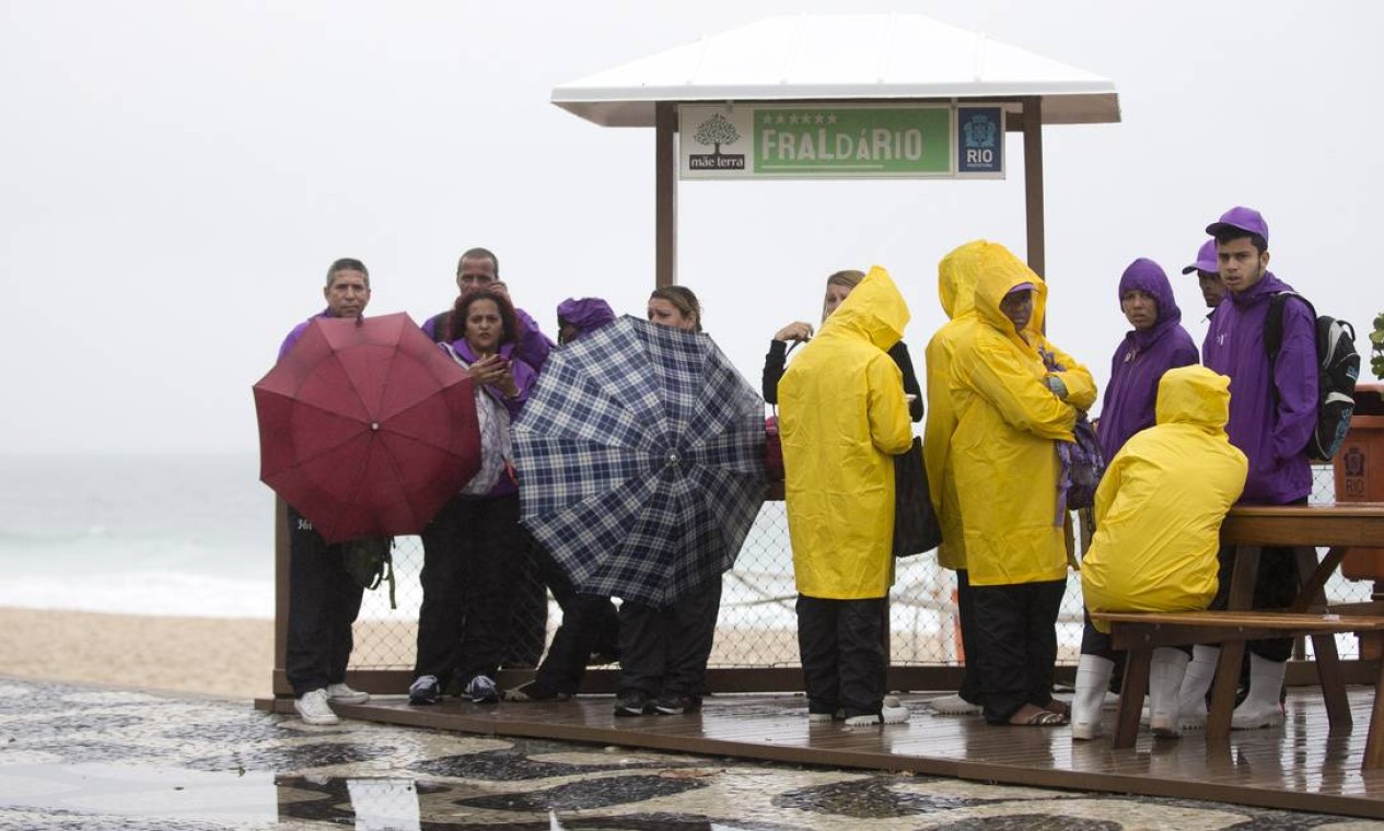 Outro grupo se protege da chuva Foto: Márcia Foletto / Agência O Globo