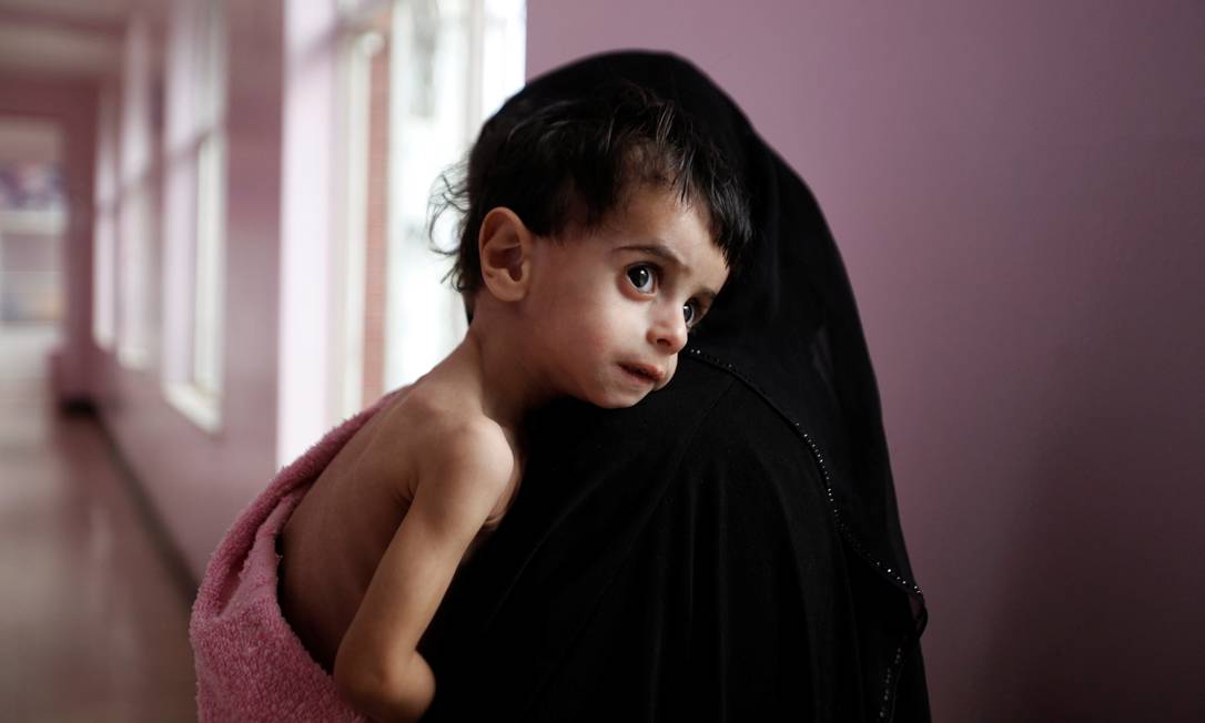 Uma mulher carrega seu filho, internado por desnutrição em um hospital em Sanaa, no Iêmen. Em guerra civil, país sofre com escassez de alimentos Foto: KHALED ABDULLAH / Agência O Globo