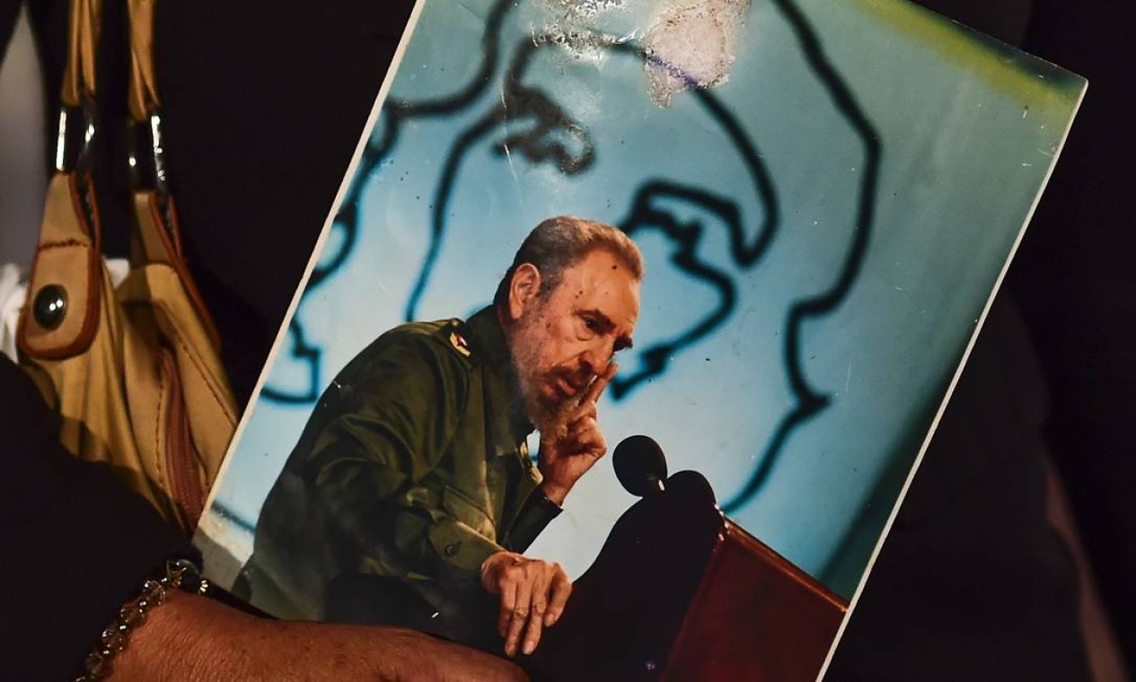 Uma mulher segura uma foto de Fidel Castro, enquanto espera na fila Foto: RONALDO SCHEMIDT / AFP