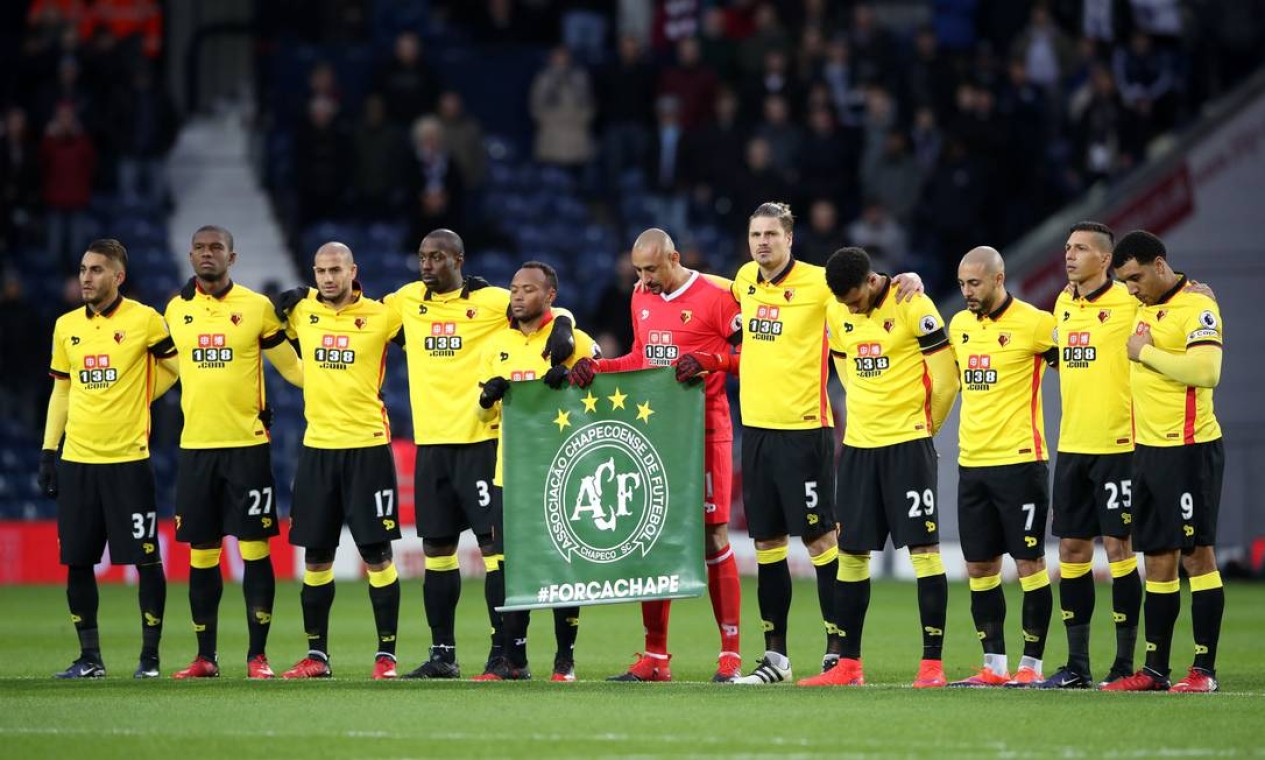Jogadores do Watford fazem um minuto de silênco em homenagem à Chapecoense. O goleiro brasileiro Gomes é um dos que seguram a bandeira da equipe brasileira Foto: Nick Potts / AP