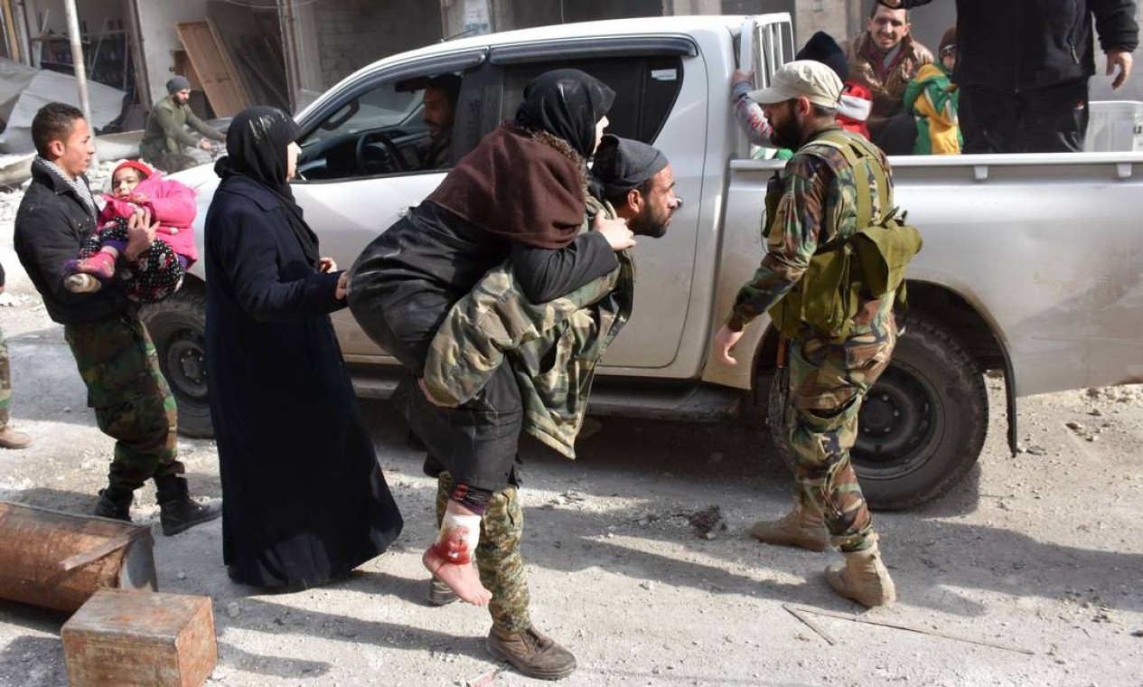 Combatente pró-governo carrega nos braços uma mulher que foi ferida enquanto tentava fugir com a sua família dos combates em Aleppo Foto: GEORGE OURFALIAN / AFP
