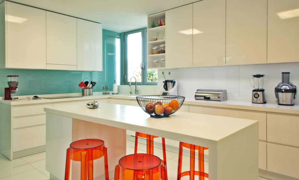 A arquiteta Andrea Chicharo deu vida à cozinha predominantemente branca com uma parede verde-água e bancos laranjas Foto: Divulgação