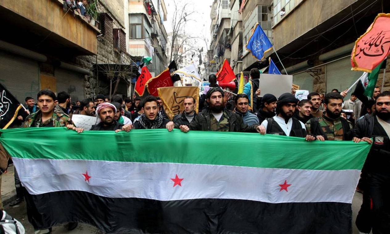 Membros do Exército Livre da Síria carregam grande bandeira da oposição em protesto contra al-Assad Foto: MUZAFFAR SALMAN / REUTERS