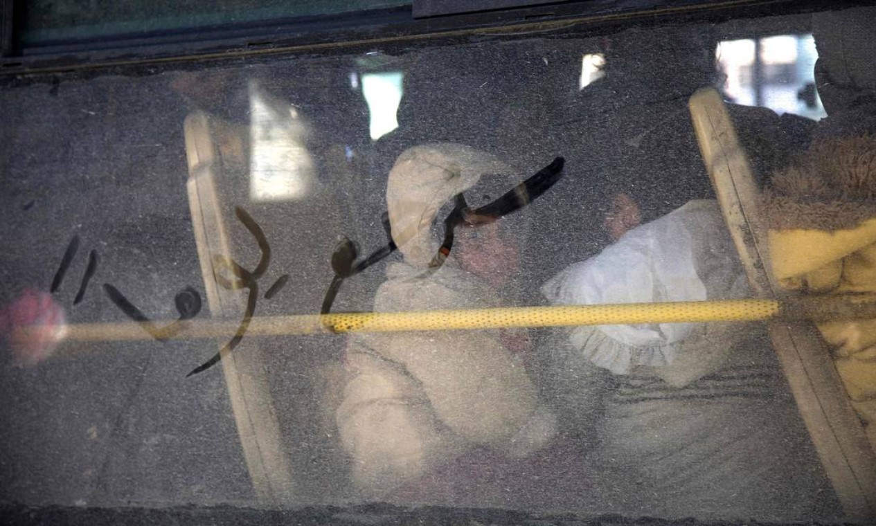 Crianças também são transportadas por ônibus em retirada de Aleppo; na janela, palavras em árabe dizem "um dia nós vamos voltar" Foto: KARAM AL-MASRI / AFP