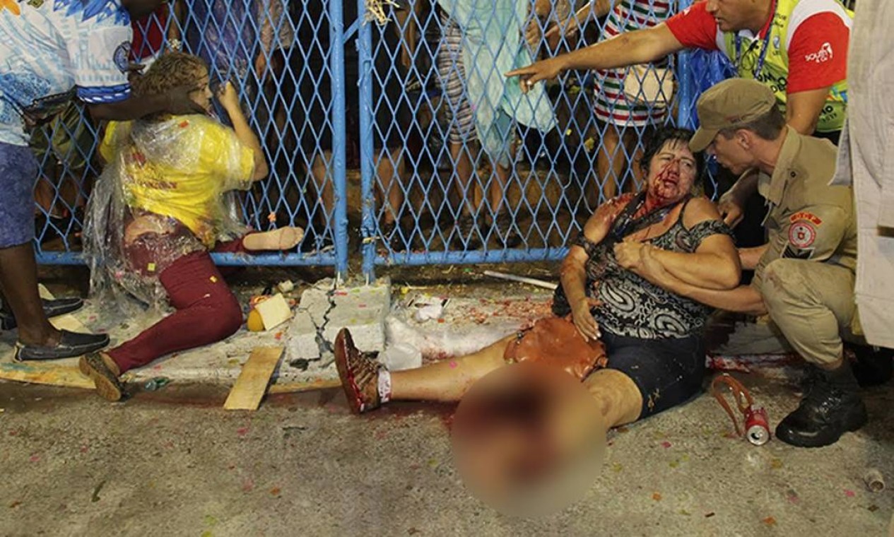 Com fratura exposta na perna esquerda, uma das vítimas recebe atendimento junto à grade atingida pelo carro alegórico da Paraíso do Tuiuti Foto: Marcelo Theobald/O GLOBO