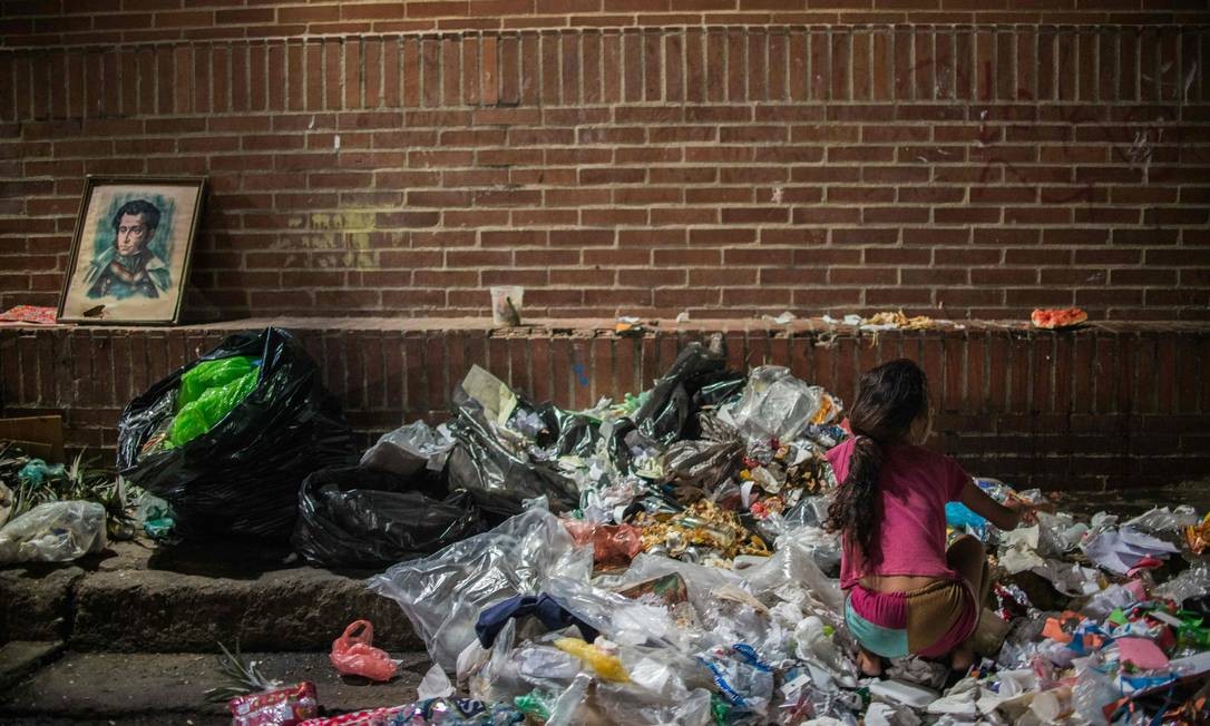 Menina confere restos de comida em lixo em Caracas Foto: FEDERICO PARRA / AFP