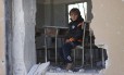 
O garoto sírio Ahmed, de 6 anos, se senta em uma escola destruída, em Idlib, no norte da Síria
