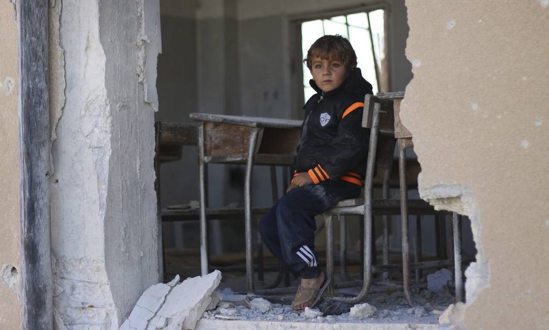 O garoto sírio Ahmed, de 6 anos, se senta em uma escola destruída, em Idlib, no norte da Síria Foto:
Uncredited
/
AP
