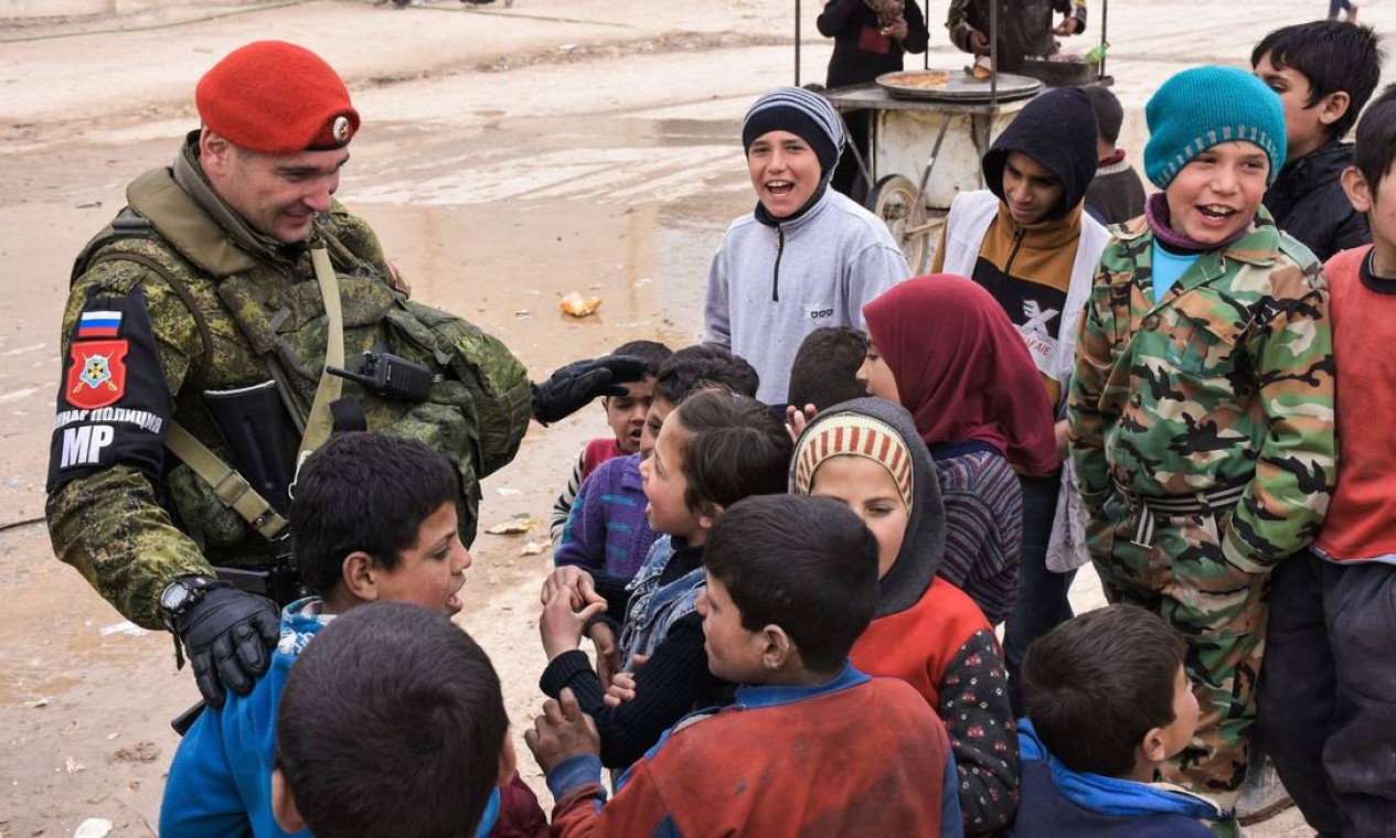Militar russo conversa com crianças sírias deslocadas, enquanto Exército de Moscou distribuía vacinas e ajuda médica para hospitais pediátricos em abrigos de Jibreen, perto de Aleppo Foto: GEORGE OURFALIAN / AFP