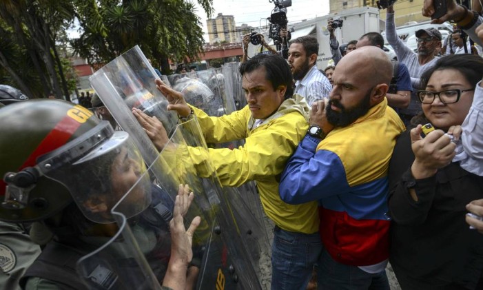Deputados de oposição venezuelanos Carlos Paparoni e Marco Bozo brigam com a Guarda Nacional durante protesto Foto: JUAN BARRETO / AFP