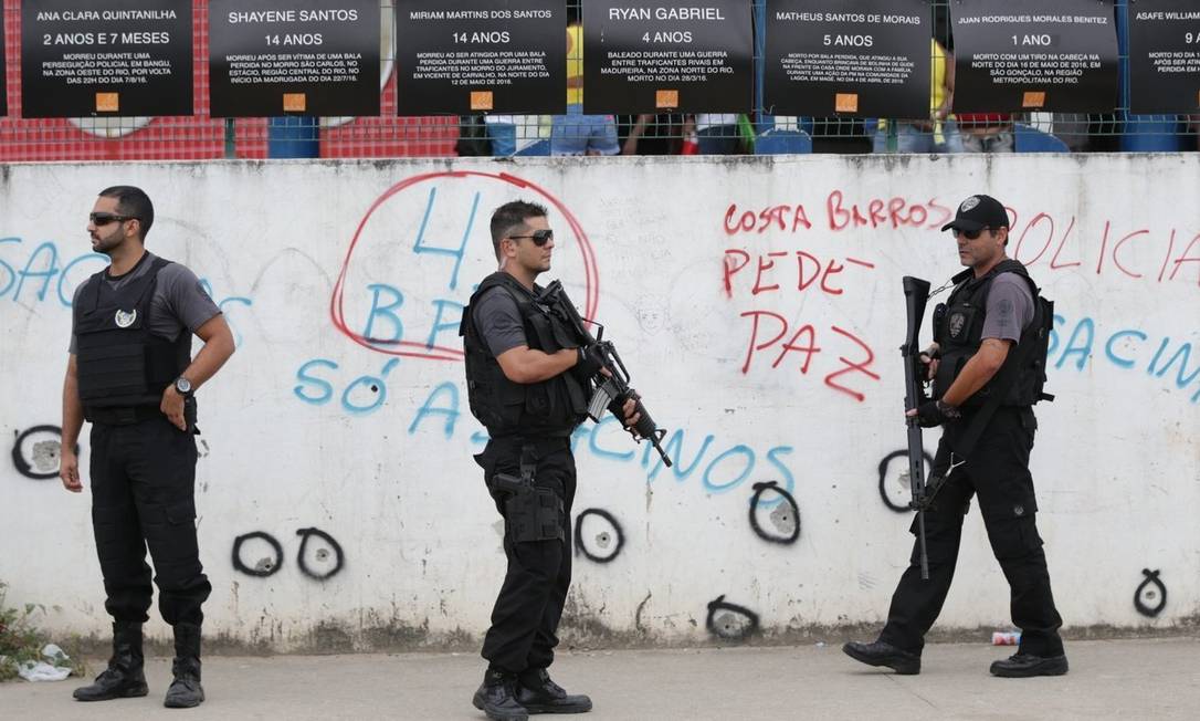 Marcas do confronto. Policiais junto ao muro da unidade de ensino Foto: Marcio Alves / Márcio Alves