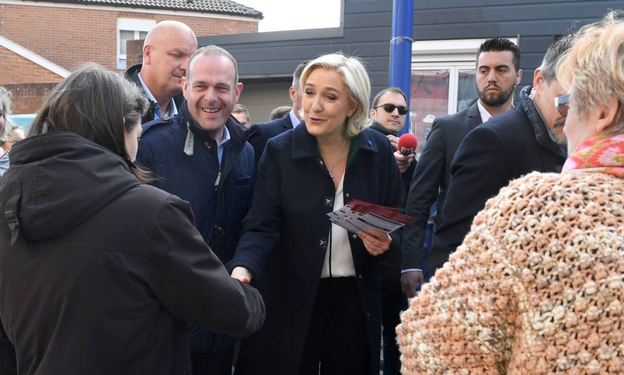 A candidata francesa de extrema-direita, Marine Le Pen, acompanhada pelo vice-presidente do seu partido, a Frente Nacional (FN), e pelo prefeito de Henin-Beaumont, Steeve Briois, encontra-se com moradores locais. Ela e Macron são os dois candidatos que irão ao segundo turno das eleições presidenciais Foto: ALAIN JOCARD / AFP