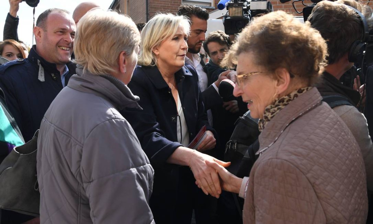 A candidata da extrema-direita, Marine Le Pen, se encontra com franceses durante uma visita ao mercado em Rouvry, próximo a Henin-Beaumont, no Norte da França. Le Pen tenta ganhar a simpatia da extrema-esquerda, que já negou apoio ao candidato centrista Foto: ALAIN JOCARD / AFP