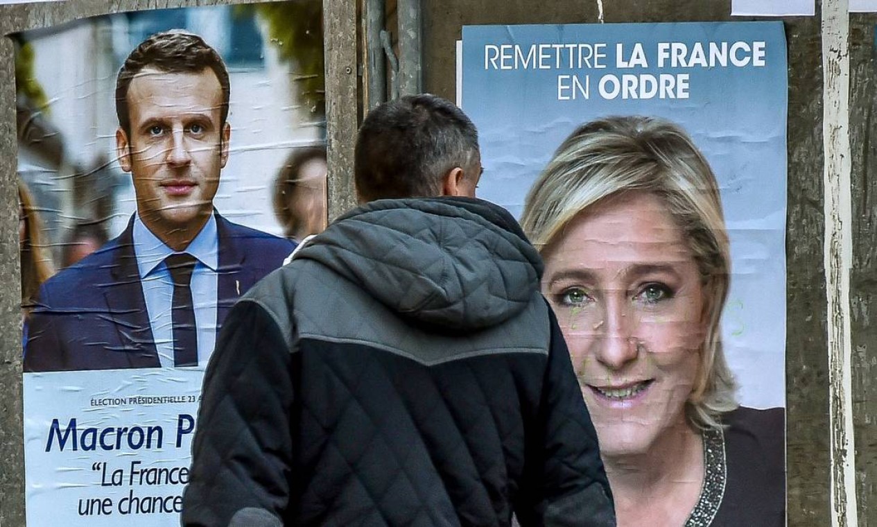 Morador de Lille olha os pôsteres dos candidatos à Presidência francesa Emmanuel Macron, do movimento Em Marcha!, e Marine Le Pen, do partido de extrema-direita Frente Nacional (FN). Macron e Le Pen têm 15 dias para convencer os 47 milhões de eleitores Foto: PHILIPPE HUGUEN / AFP