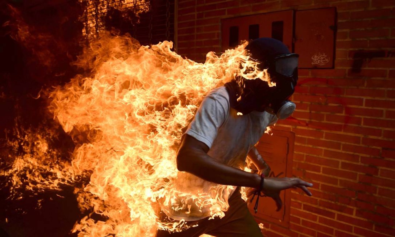 Manifestante pega fogo durante confrontos com a polícia durante protesto contra o presidente venezuelano, Nicolás Maduro, em Caracas Foto: RONALDO SCHEMIDT / AFP