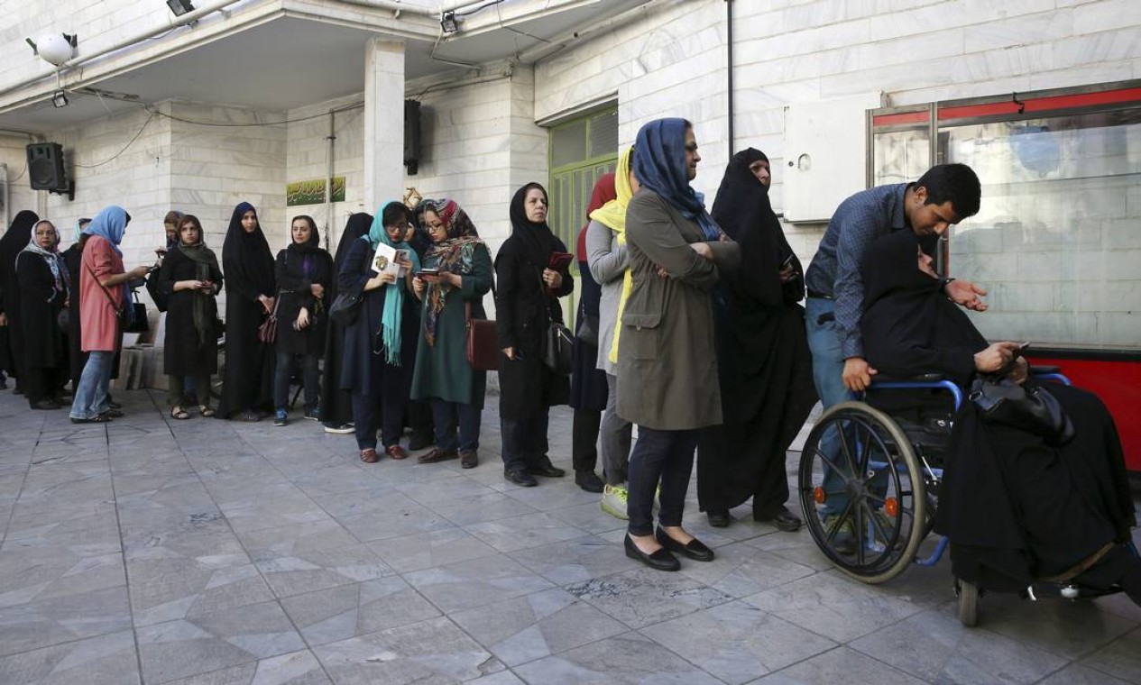 Iranianos fazem fila em um sessão eleitoral para votar nos candidatos presidenciais e municipais, em Teerã. Os eleitores se pronunciarão entre a manutenção da política de abertura promovida por Rouhani e o nacionalismo defendido por Raisi Foto: Vahid Salemi / AP