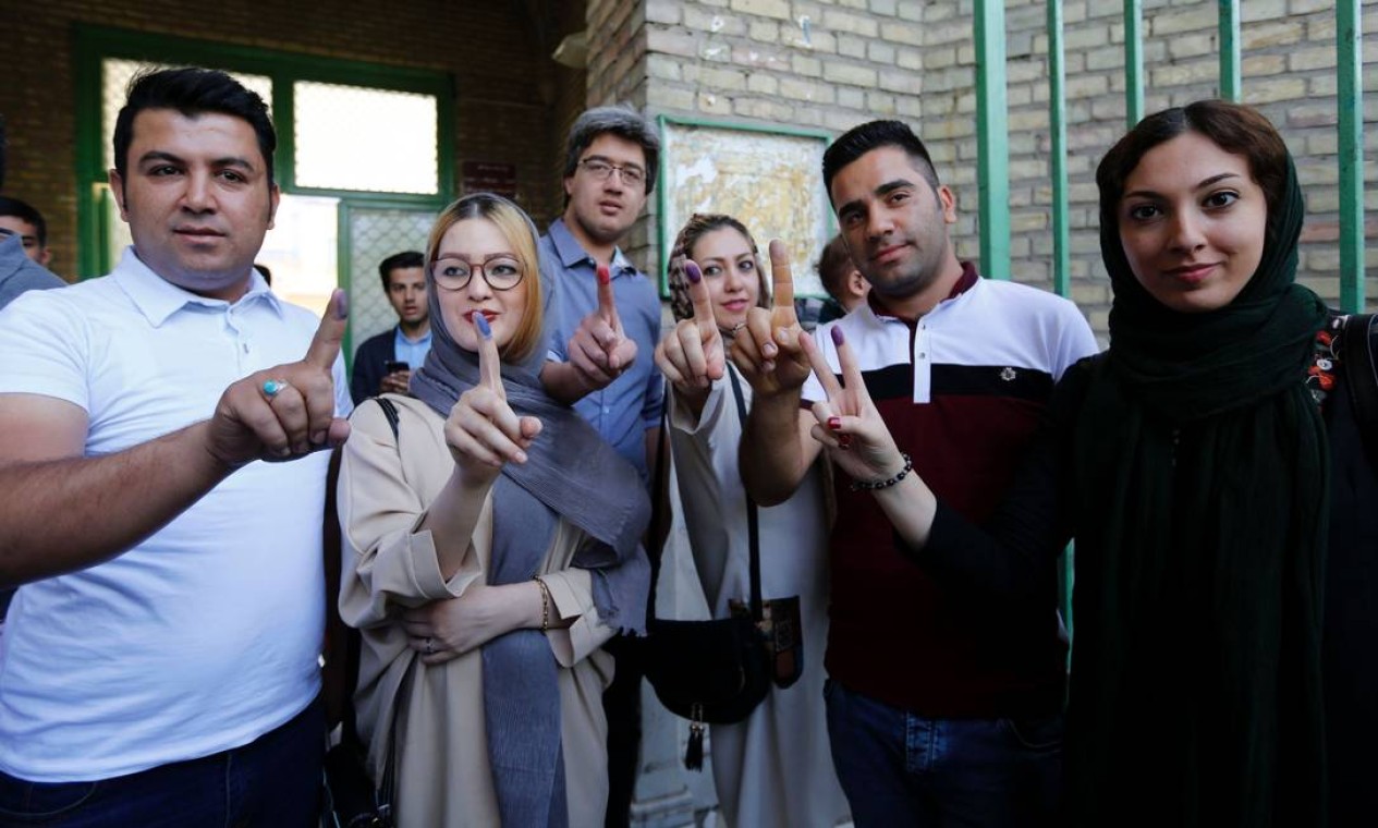 Iranianos mostram seus dedos pintados após votar nas eleições presidenciais em uma sessão eleitoral em Teerã. Muitos eleitores tinham dúvidas em quem votar. Enquanto alguns diziam que iriam boicotar a eleição, outros queriam votar para expressar sua raiva sobre a economia combalida Foto: ATTA KENARE / AFP