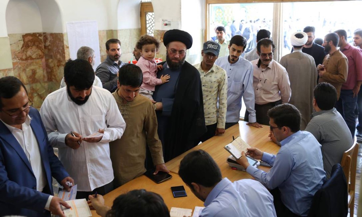 Homens chegam para votar na cidade de Qom, 130km ao Sul de Teerã. O atual presidente do país, Hassan Rouhani, tenta a reeleição após o acordo nuclear com as potências mundiais em 2015 que diminuiu o programa nuclear do país Foto: ALI SHAIGAN / AFP
