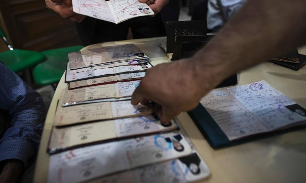 Um funcionário das eleições iranianas checa as identidades dos eleitores em uma sessão eleitoral em Teerã Foto: BEHROUZ MEHRI / AFP