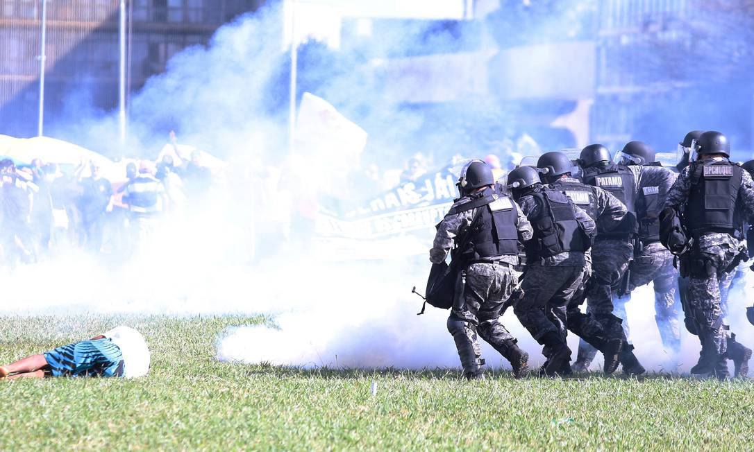 Tropa policial avança enquanto manifestante fica caído no gramado Foto: Jorge William / O Globo