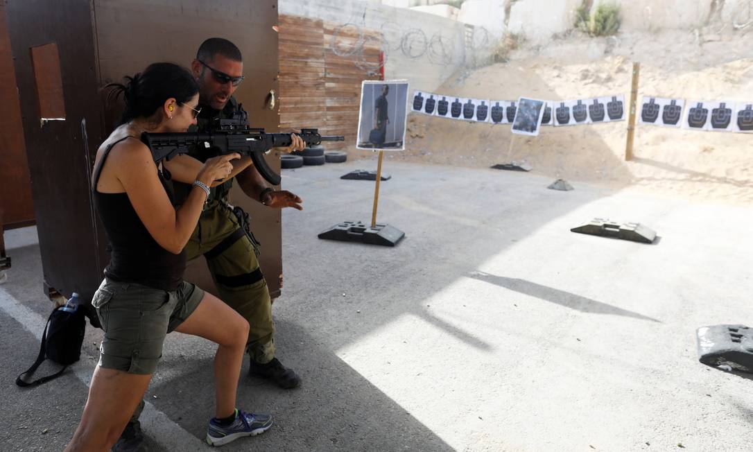 Instrutor israelense ensina a uma turista como empunhar uma arma no Caliber 3, centro de treinamento antiterrorismo na Cisjordânia Foto: NIR ELIAS / REUTERS