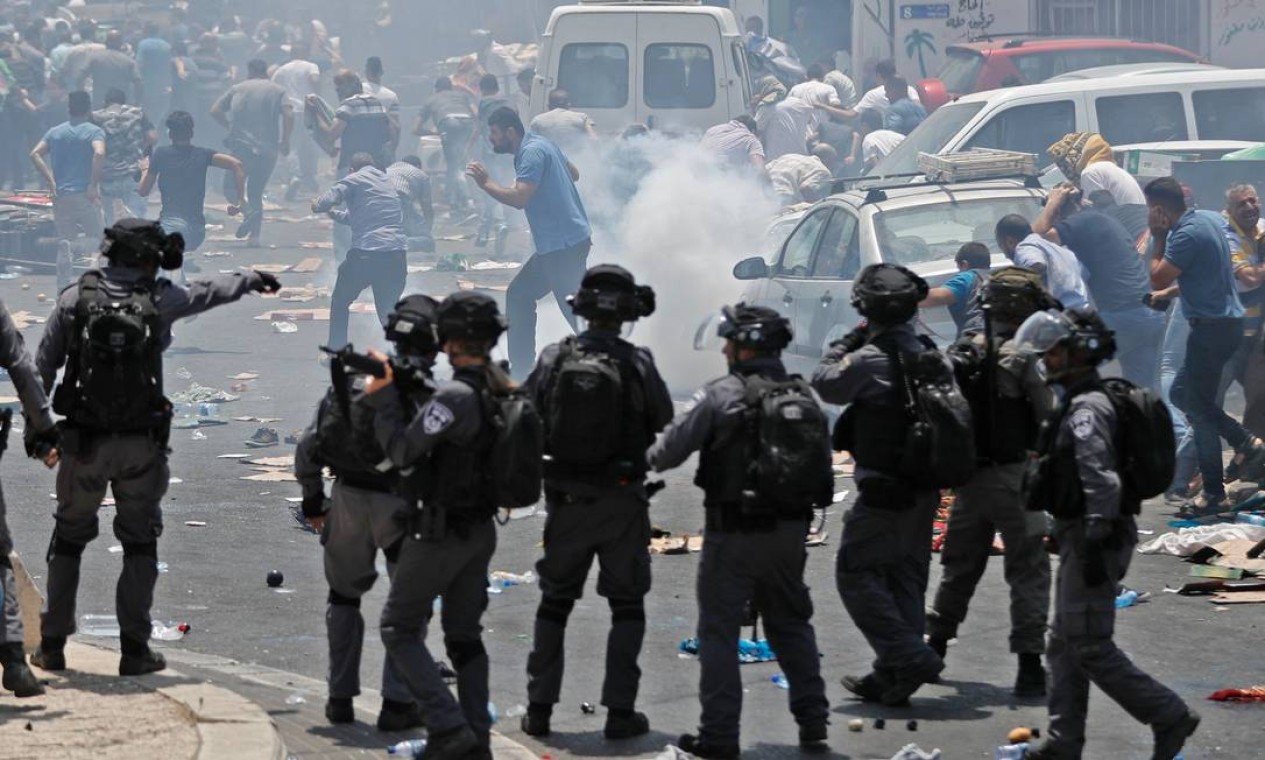 Palestinos correm fugindo do gás lacrimogêneo lançado por policiais israelenses, após as orações de sexta-feira na Cidade Velha de Jerusalém Foto: AHMAD GHARABLI / AFP