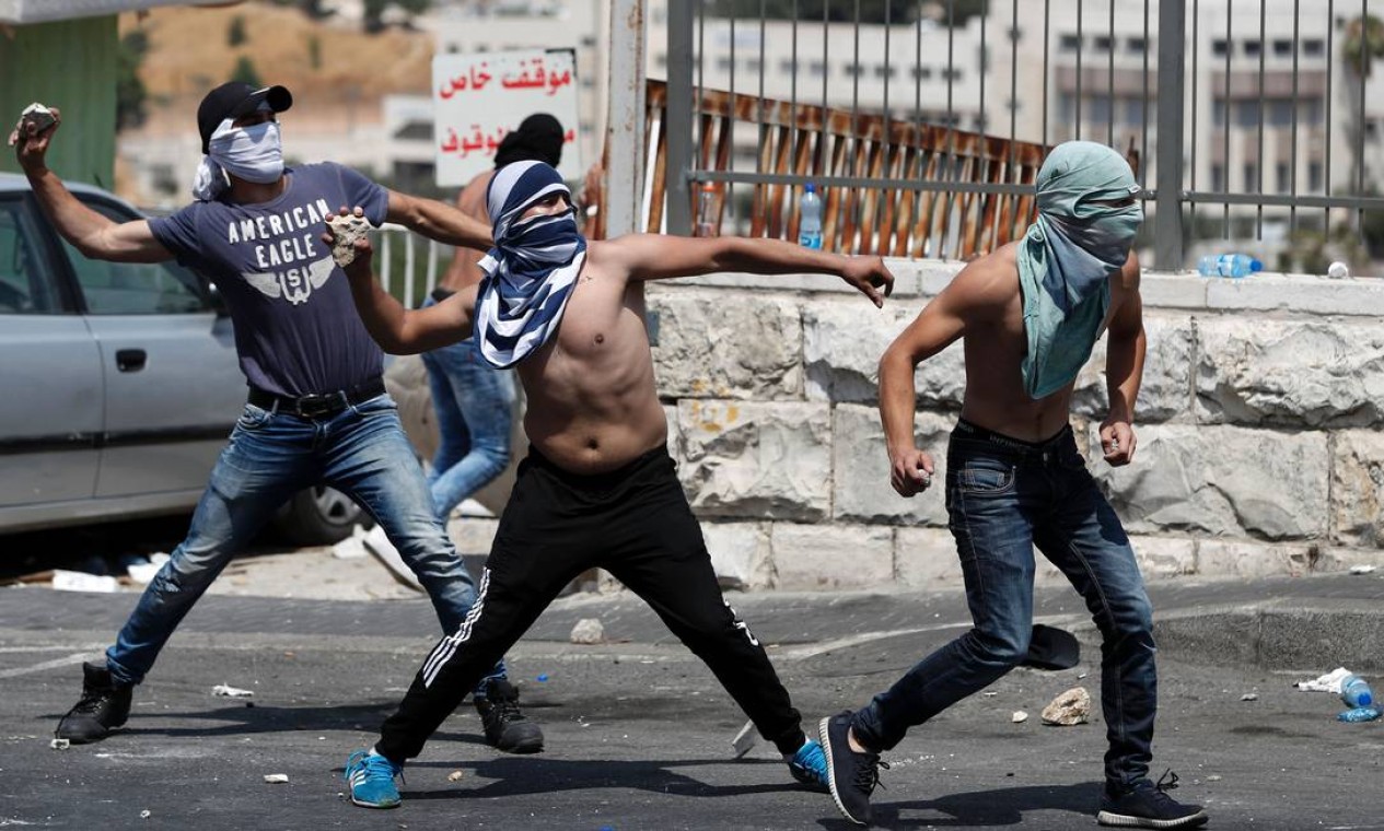 Jovens palestinos jogam pedras contra as forças de segurança israelenses durante protestos. Policiais responderam com gás lacrimogêneo Foto: AHMAD GHARABLI / AFP