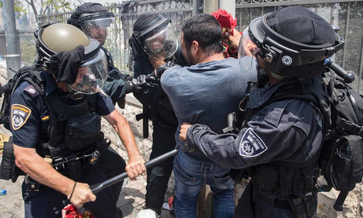 Policiais israelenses brigam com um homem durante protestos na Cidade Velha de Jerusalém. Ao menos dois palestinos morreram e cerca de 200 ficaram feridos em confrontos com a polícia israelense nos arredores da Esplanada das Mesquitas Foto: JACK GUEZ / AFP