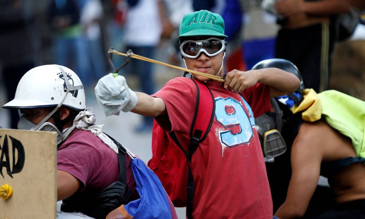 Jovem usa um estilingue durante um protesto contra o presidente venezuelano, Nicolás Maduro, em Caracas Foto: ANDRES MARTINEZ CASARES / REUTERS