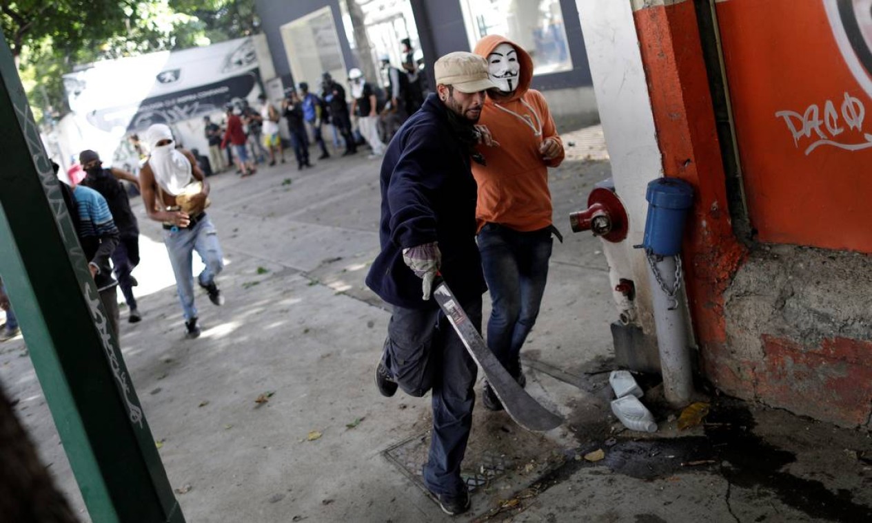 Manifestantes correm durante protesto contra o presidente venezuelano, Nicolás Maduro, em Caracas. Confrontos com a polícia durante a greve geral convocada pela oposição já deixaram um morto e dezenas de feridos Foto: UESLEI MARCELINO / REUTERS