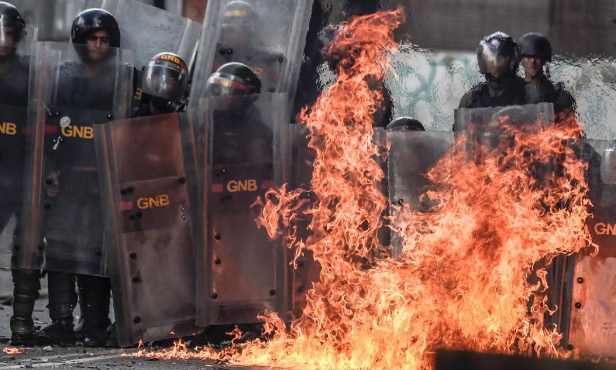 Um coquetel molotov é jogado por ativistas contra o governo e explode próximo a membros da Guarda Nacional Bolivariana (GNB) em Caracas Foto: JUAN BARRETO / AFP