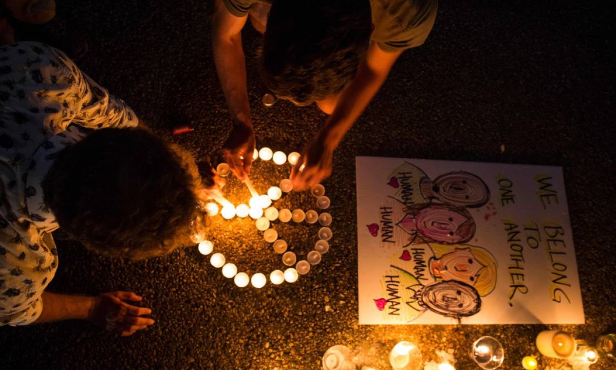 Pessoas acendem velas em formato de símbolo de paz em frente à Casa Branca, no domingo, dia 13 de agosto, em Washington DC, durante vigília em homenagem à vítima do acidente de Charlottesville Foto: ZACH GIBSON / AFP
